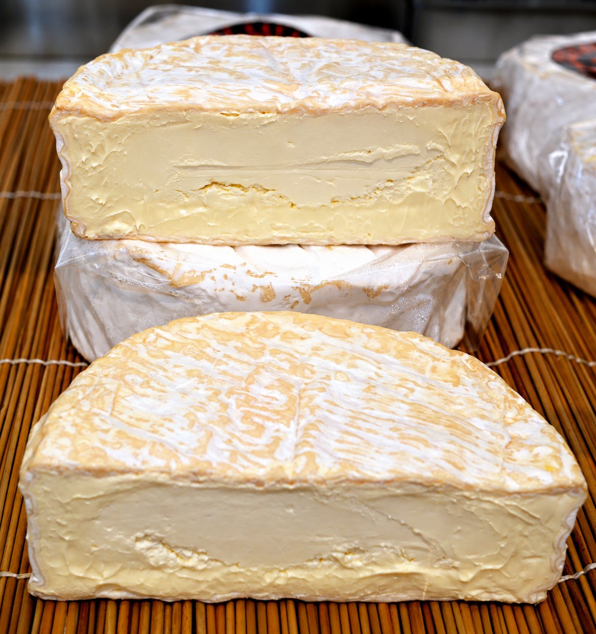 Des fromages à croûte fleurie coupés sur un tapis en bambou.