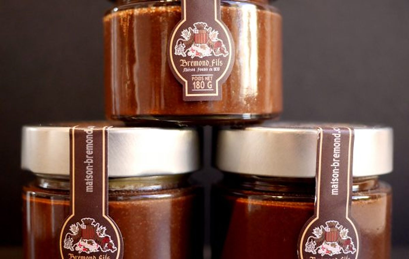 Trois pots en verre de pâte à tartiner au chocolat de la maison Bremond Fils, empilés devant un fond sombre.