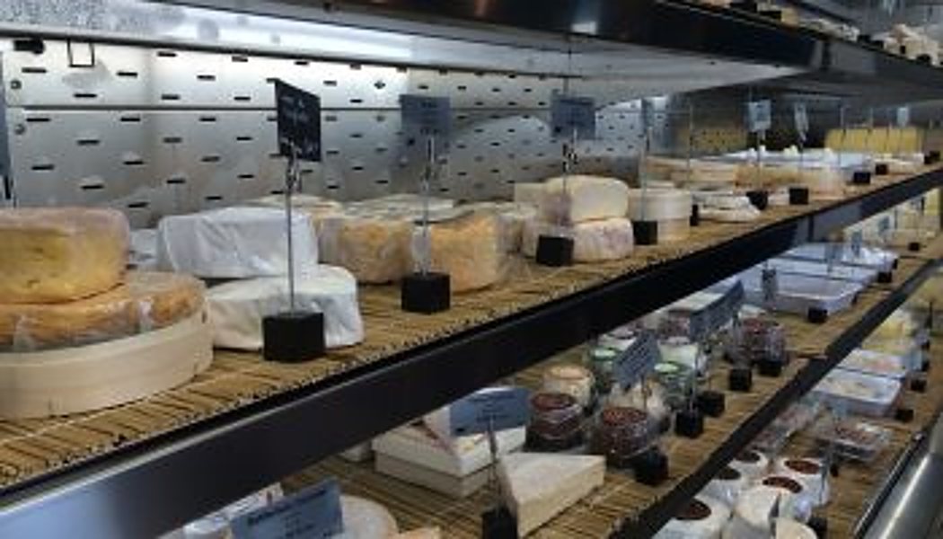 La vitrine réfrigérée de la cave à fromages, avec ses étagères en bois et ses petites ardoises sur pied.